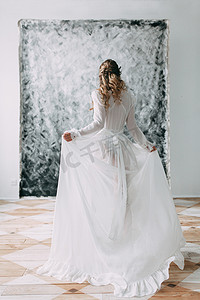 美丽的年轻新娘在闺房的衣服上的画布背景与油漆。婚礼的趋势和想法 2018, 春天的灵感。婚礼在演播室