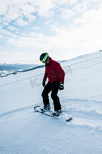 头戴安全帽的滑雪者，冬季乘着白雪骑在斜坡上 