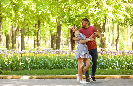 快乐的年轻夫妇在绿色公园在阳光明媚的春天天