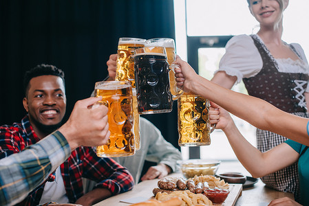 欢快的多元文化朋友在酒吧庆祝十月节时，会喝杯啤酒