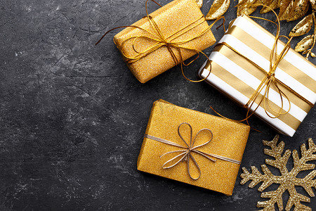 黑色石头背景的金色礼品盒，复制空间平铺，圣诞贺卡