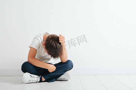 一个抑郁的孩子坐在地板上