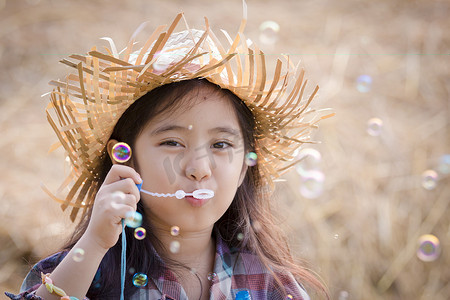 快乐的亚洲孩子玩稻草堆栈的泡泡