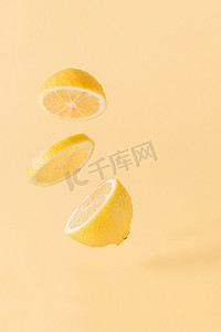 背景淡黄色摄影照片_一片健康的、有机的、新鲜的、多汁的柠檬片，漂浮在淡黄色的背景之上。最少夏天柑橘类水果的排列。自然排食物概念.