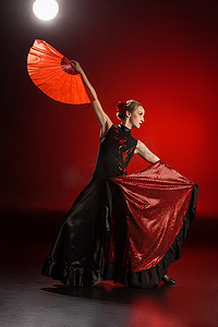 雅致的弗拉门戈舞者在红色的舞姿中，触摸着衣服，握着扇子 