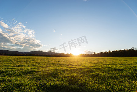 远离伤胃摄影照片_美丽的绿色草地，夕阳西下，远离小山.