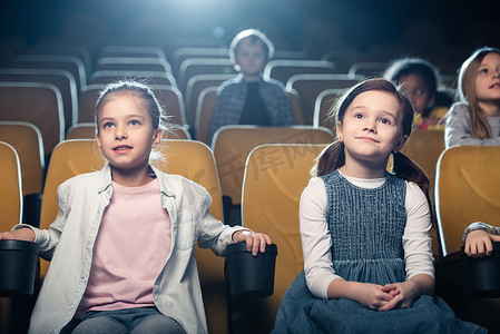与多元文化的朋友一起在电影院看电影的微笑的孩子们