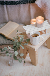 室内静物细节︰ 针织衣服老式的木地板上杯茶，蜡烛和书