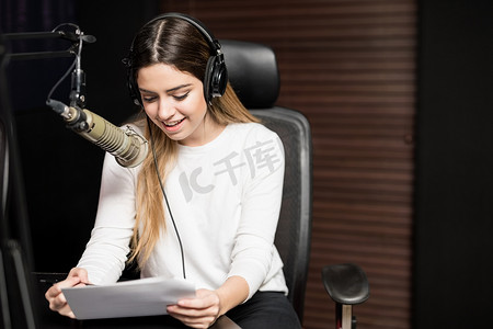 在电台用耳机和麦克风拍摄的年轻女性无线电主持人肖像