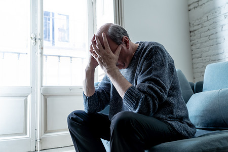 不堪重负的老老人独自在家中感到困惑的悲伤独自在家中的沙发在老龄化退休鳏夫痴呆和阿尔茨海默症概念.