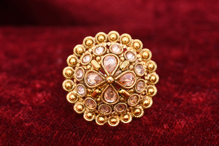 珠宝红色摄影照片_花式设计师珍贵的珠宝金色戒指特写镜头宏观图像在红色背景上的女人