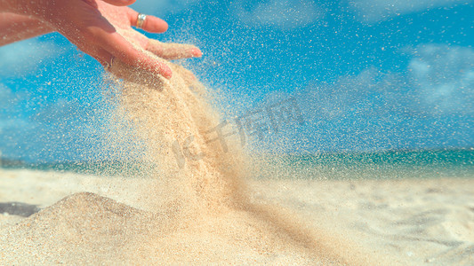 Girl摄影照片_CLOSE UP: Unknown young woman lets sand fall from her soft hands and back on the tranquil tropical shore. Summer wind scatters sand out of girl's grasp and across the beautiful paradise island beach.