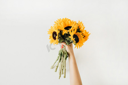 向日葵花束在妇女手中。平坦的布局,顶景夏季花卉组合.
