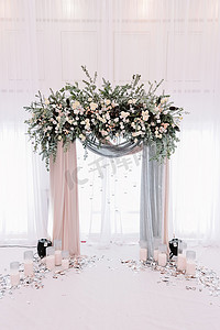 美丽的婚礼拱门。桃色和银色布和鲜花装饰的拱门