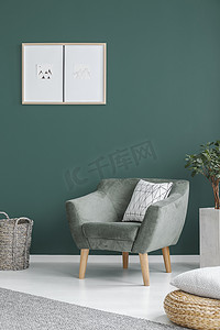 植物旁边的绿色扶手椅与枕头在客厅内墙上的海报