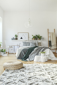 现代居室内带海报的灰色、绿色床上用品在脚凳上的图案地毯