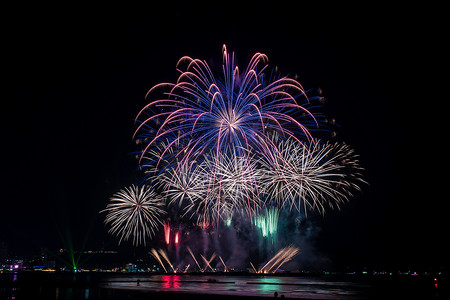 在庆祝之夜精彩美丽的五彩缤纷的烟火表演，在海滩上展示，在水面上有多种颜色的倒影 