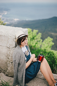 时尚fashion摄影照片_Young fashion woman sitting on a top of the mountain drinking tea