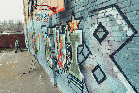 男子在墙上用篮球圈画彩色涂鸦