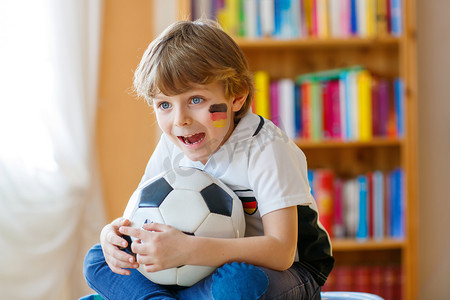 儿童足球队摄影照片_孩子男孩看足球赛或电视上的足球比赛