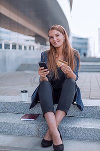 拿着智能手机和信用卡的年轻女人