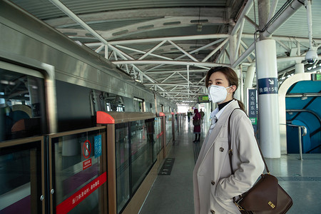 戴口罩的年轻女人站在地铁站台上