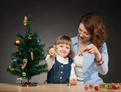 钟声敲响摄影照片_幸福微笑的女婴和她的木乃伊装饰圣诞树