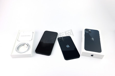 促销活动扁平风摄影照片_促销活动期间，苹果商店的白色架子上陈列着黑色的苹果手机iphone 13和白色的包装