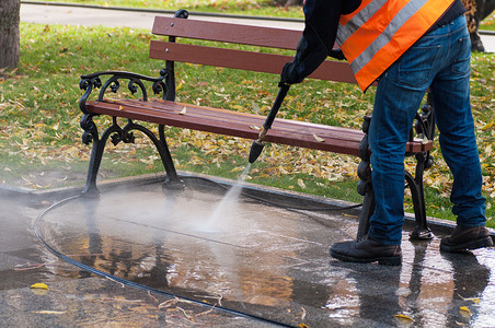 秋天用清水清洁公园。一个工人清扫公园