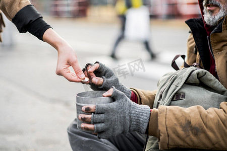 城市里的一个中段妇女给无家可归的乞丐人捐款的全景.