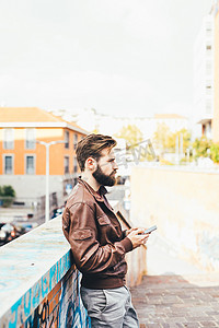手机大摄影照片_年轻英俊的大胡子男子使用智能手机观看流媒体视频