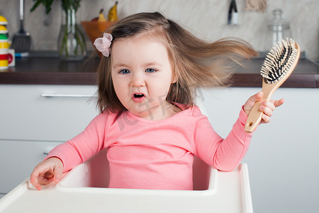 女孩2年在家里玩梳子-学习梳她的长发, 翻腾做滑稽和严肃的面孔