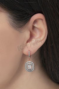 银质的耳环挂在一个修整过的女士的耳朵上.可用于电子商务销售的珠宝图像.