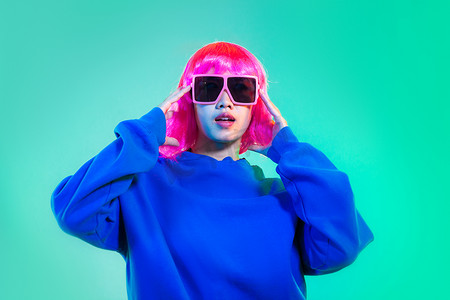 short摄影照片_Young asian woman in blue sweatshirt pink short hair punk style wearing sunglasses posing dancing on the green screen background.
