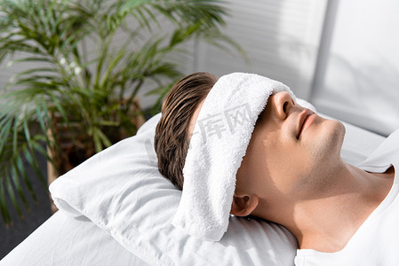 年轻人用毛巾在眼睛躺在枕头上