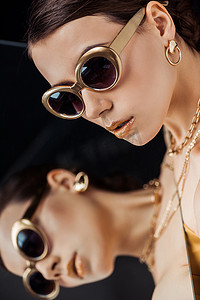 戴着太阳镜的年轻而时髦的女人，脸上挂着金光闪闪的珠宝镜子