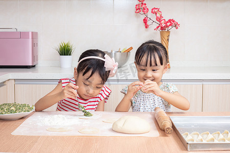 饺子摊位摄影照片_亚洲华人小姐妹家在厨房做饺子