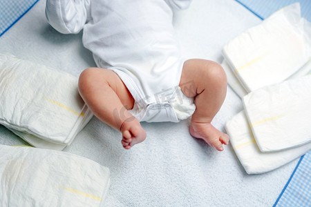 会员星期五摄影照片_用尿布把新生婴儿的脚放在更衣室的桌子上。可爱的小女孩或男孩两个星期大。干性和健康的身体和皮肤概念。幼儿保育.
