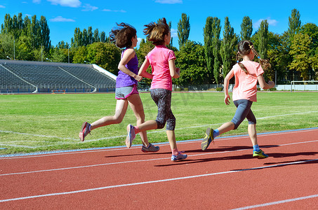 跑摄影照片_家庭体育和健身, 快乐的母亲和孩子跑在体育场跑道室外, 儿童健康活跃的生活方式概念