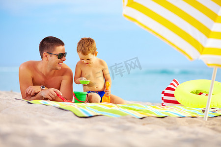 happy father and child playing in sand on the beach