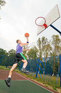 街头篮球摄影照片_Young men playing street basketball at court playground