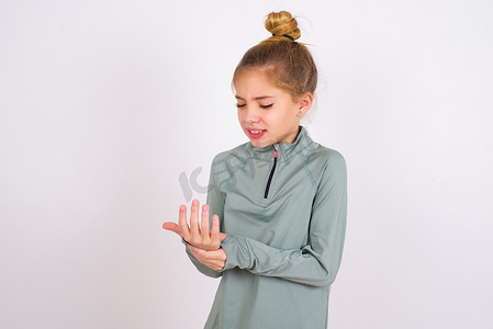 little caucasian kid girl wearing sport clothing over white background Suffering pain on hands and fingers, arthritis inflammation
