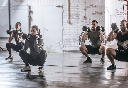 动员动员摄影照片_一群运动员和运动员在健身房蹲举重.