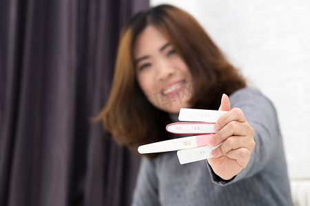 妇女手拿着排卵测试, 并试图怀孕收集尿液把测试条和阳性结果