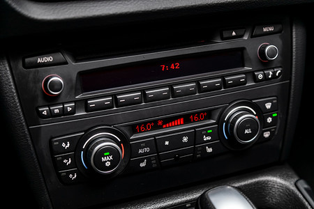 汽车黑色内饰特写：仪表盘与温度，时钟，调整鼓风机，空调等按钮。软对焦 