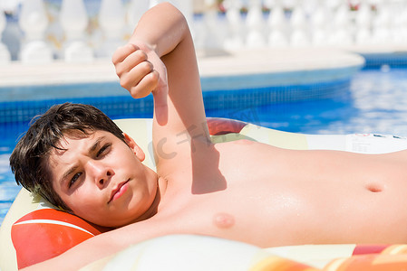 小孩子在垫假日在游泳池由海滩以愤怒的面孔, 消极标志显示不喜欢与拇指下来, 拒绝概念