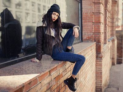pretty摄影照片_Outdoor lifestyle fashion portrait of pretty young girl, wearing in hipster swag grunge style on urban background. Wearing hat and jeans. Spring fashion woman. Toned style instagram filters.