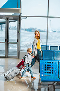 迷人的母亲与女儿牵手, 在机场与行李同行 