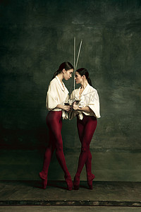 两个年轻的芭蕾舞女舞者就像拿着剑的二重唱家.芭蕾和当代编舞的概念。创意艺术照片.