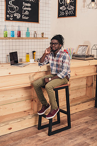 非洲裔美国人使用笔记本电脑, 并在网吧柜台上谈论智能手机